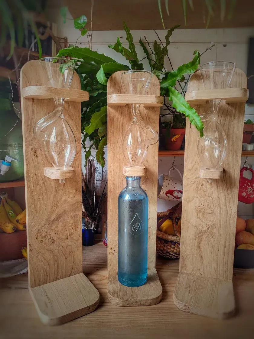 Trois Borvo en chêne massif alignés dans une cuisine, un œuf de verre dans chacun, une bouteille bleue sous celui du milieu