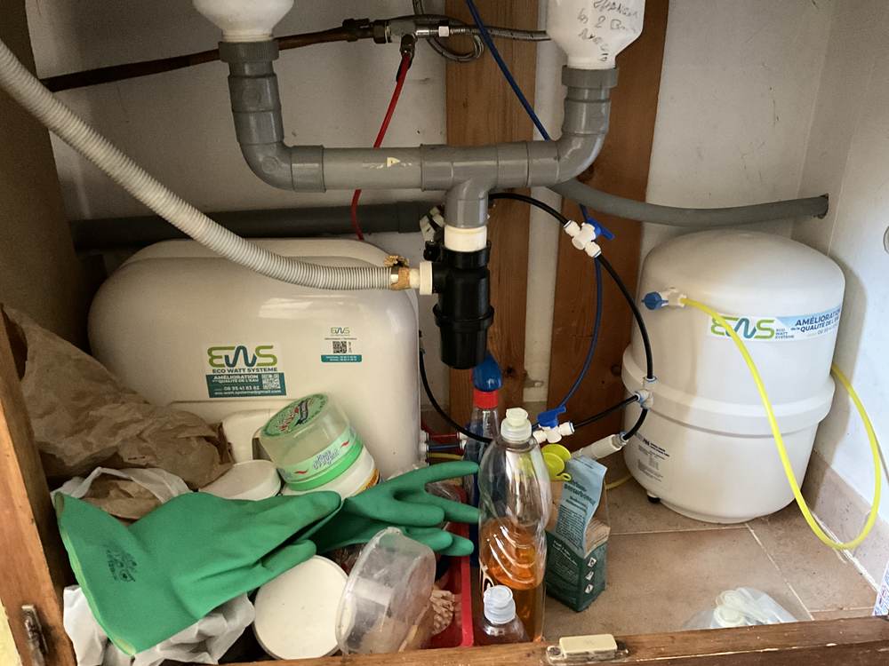 Osmoseur installé dans un meuble ancien, avec cartouche de rechange posée sur l'évier