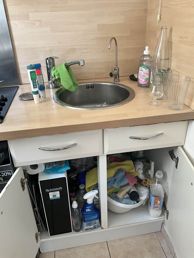Osmoseur discret dans un meuble sombre, robinet dédié visible au-dessus